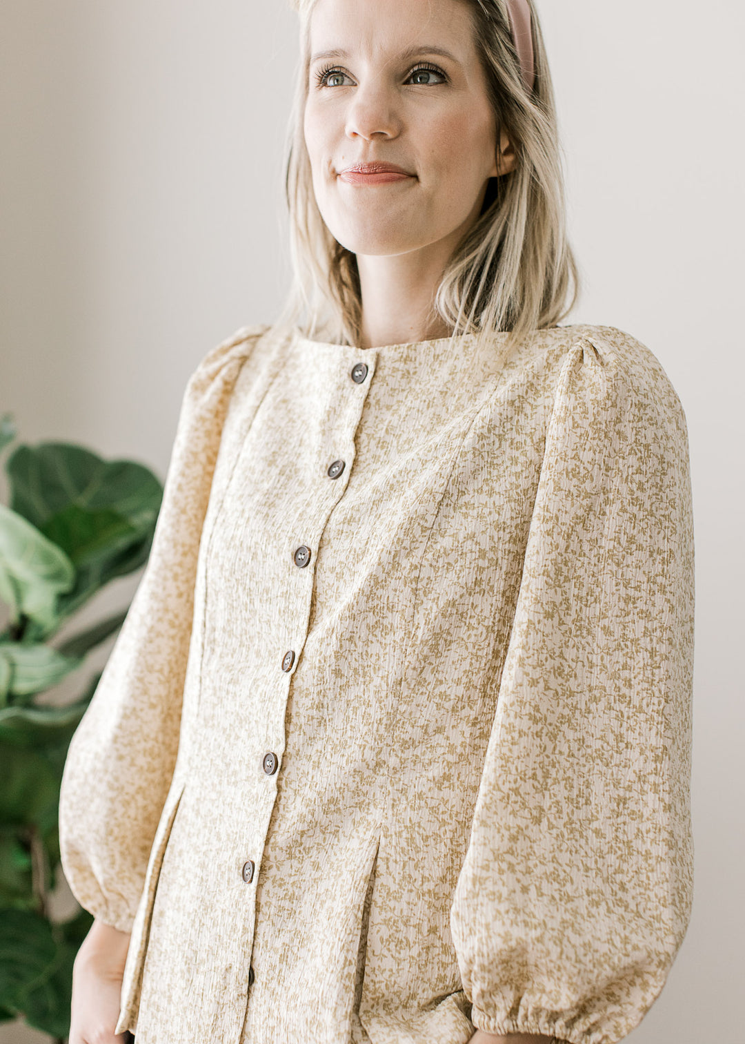 Model wearing a white top with taupe ditsy floral and 3/4-bubble sleeves with pleated shoulders.