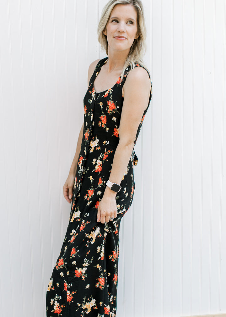 Model wearing a sleeveless black maxi with yellow and red floral a button front.