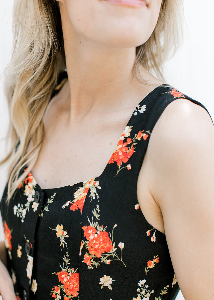 Close up of sweetheart neckline on a sleeveless black maxi with red and yellow floral. 