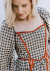 Close up of Queen Anne neckline on a brown and cream plaid top with rust detailing. 