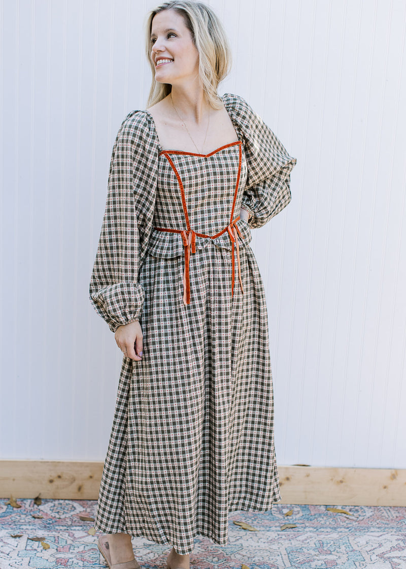 Model wearing a brown and cream plaid dress with rust detail and bubble long sleeves. 