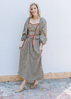 Model wearing mules with a brown and cream plaid dress with rust detail and long sleeves. 