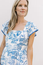 Close up of a square neck and flutter short sleeves on a maxi with toille pattern.