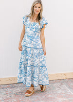 Model wearing wedges and a maxi with a toille pattern, tiered design and flutter short sleeves.