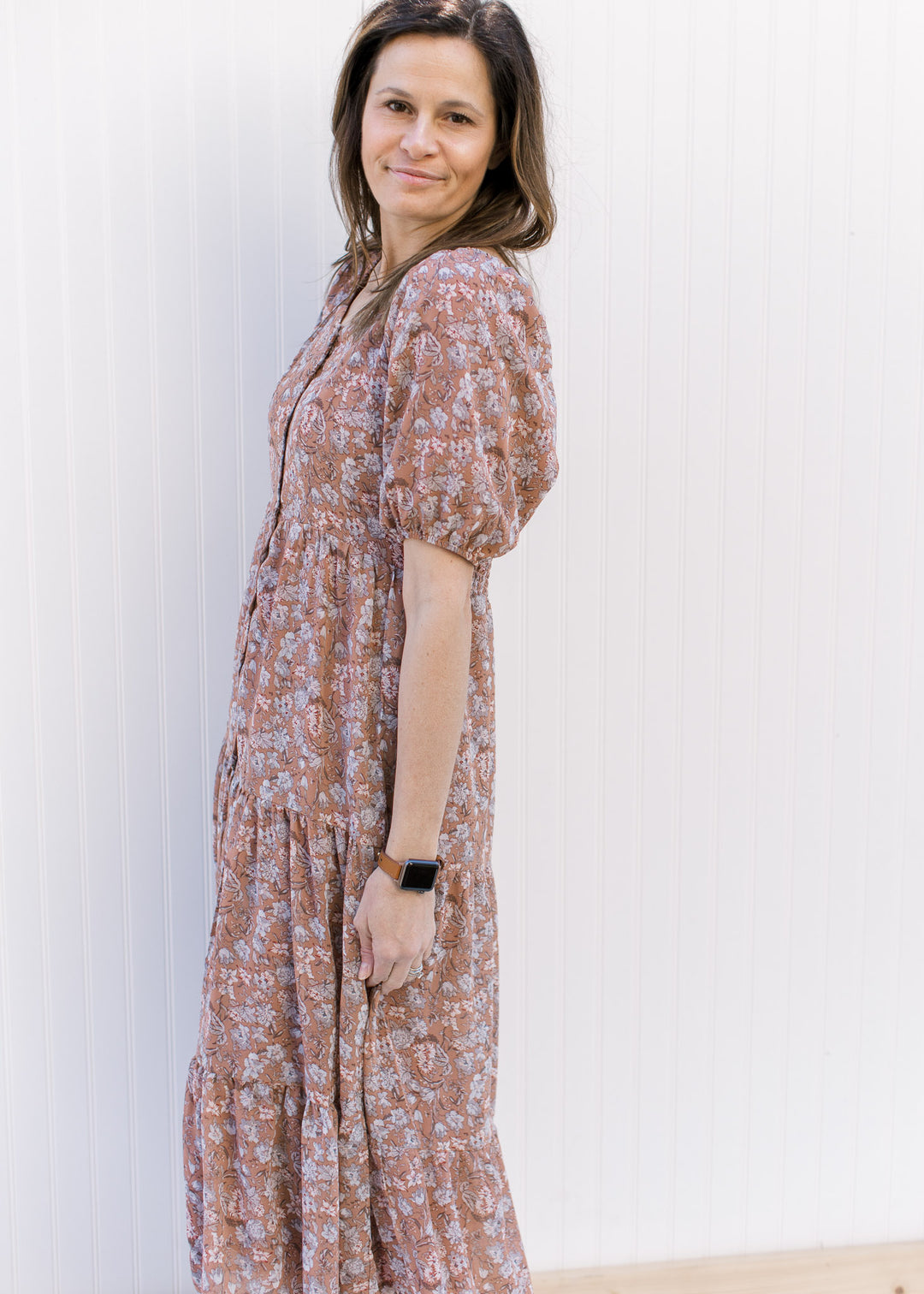Side view of Model wearing a burgundy dress with blue and cream floral, and bubble short sleeves.