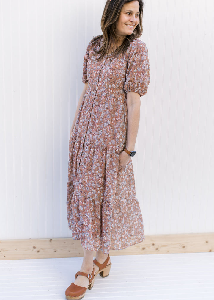 Model wearing heels and a burgundy dress with blue and cream floral, button front and short sleeves.