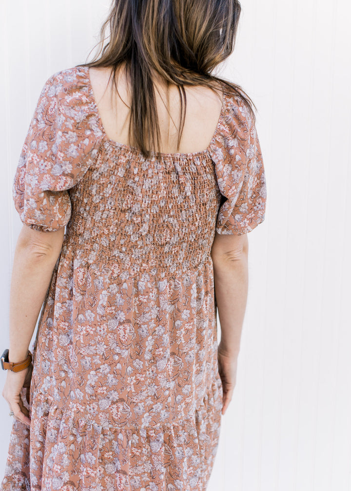 Back view of square neck and smocked back on a burgundy dress with blue and cream flowers.