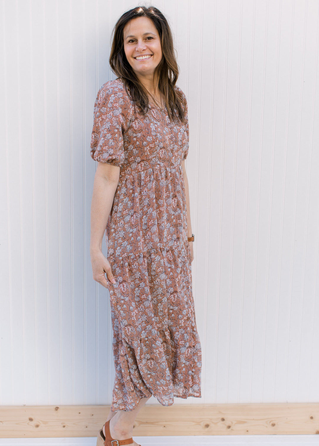 Model wearing a burgundy tiered dress with blue and cream floral and bubble short sleeves.