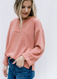 Model wearing an v-neck apricot top with a cuffed sleeve and patchwork detail.