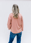 Back view of Model wearing an v-neck apricot top with a cuffed sleeve and patchwork detail.