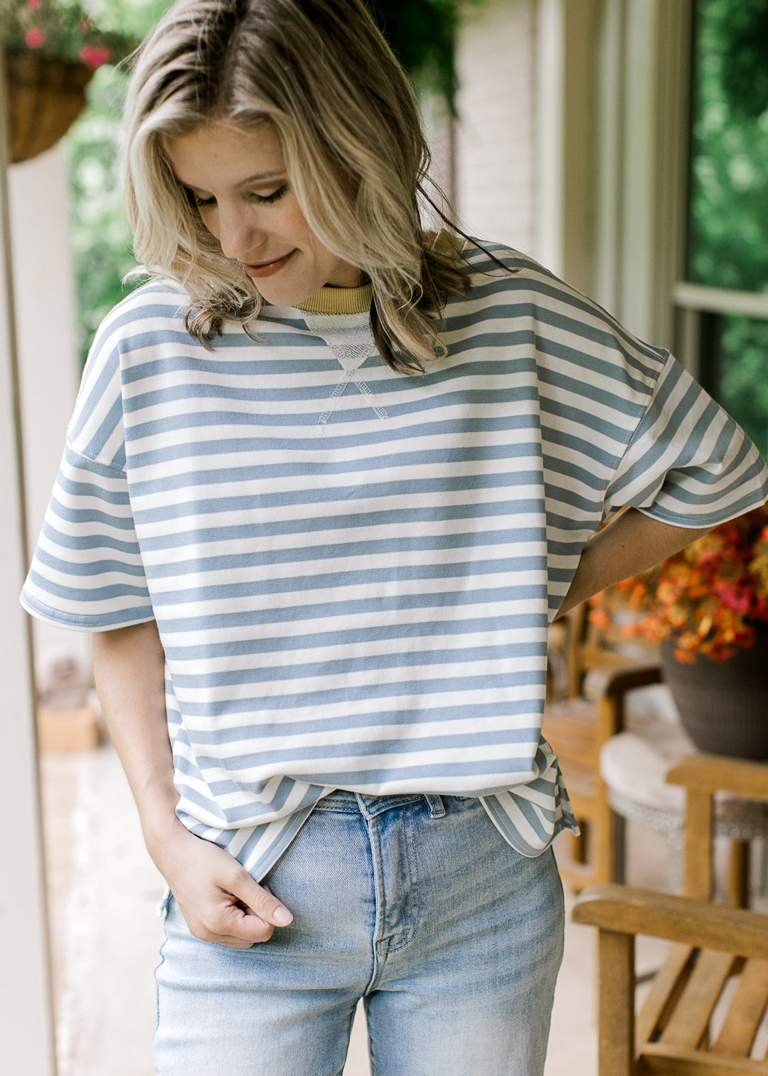 Model wearing a short sleeve dusty blue and white striped top with pale yellow ribbed round neck.