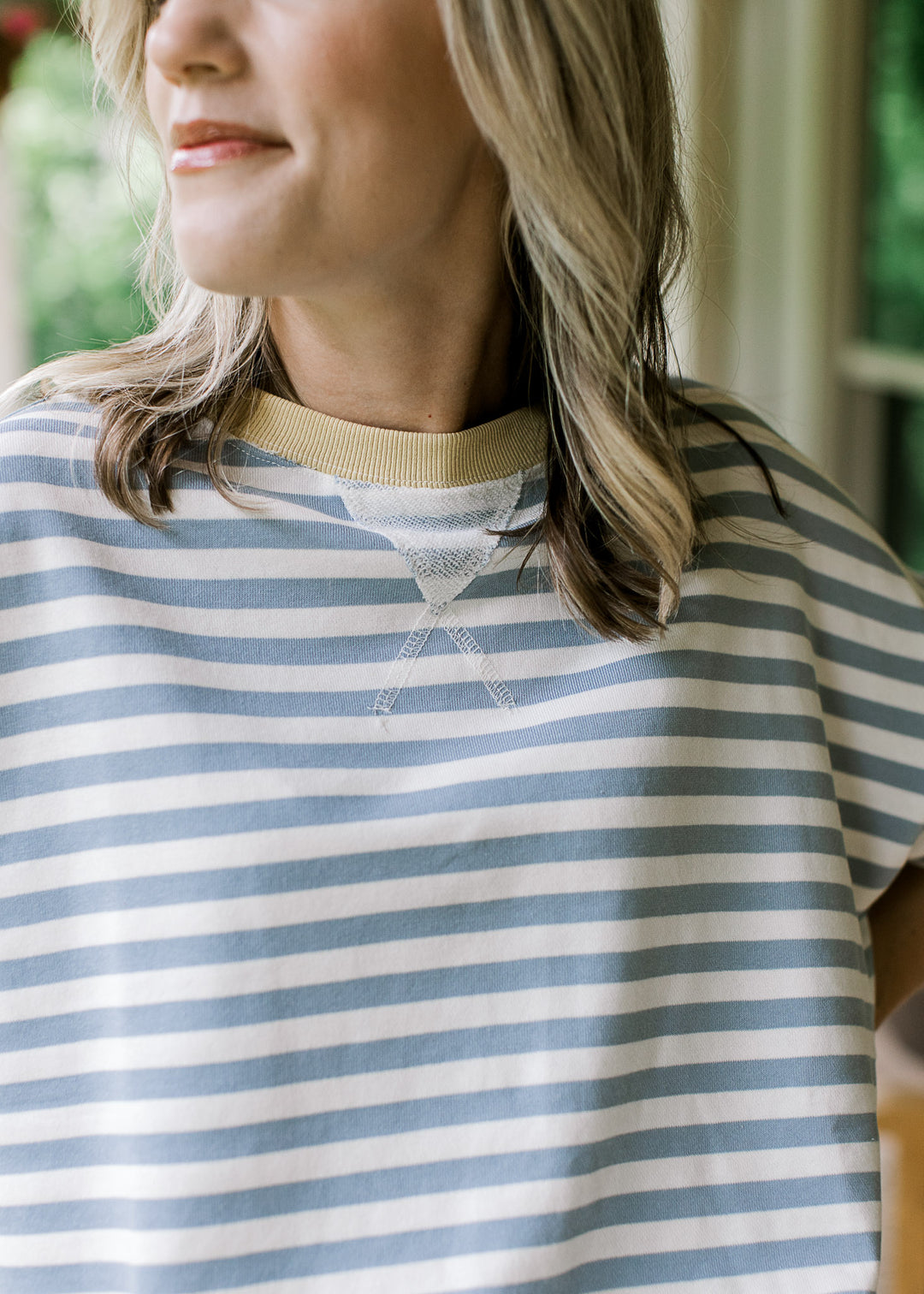 Close up of pale yellow ribbed round neckline on a pale blue and cream striped top.