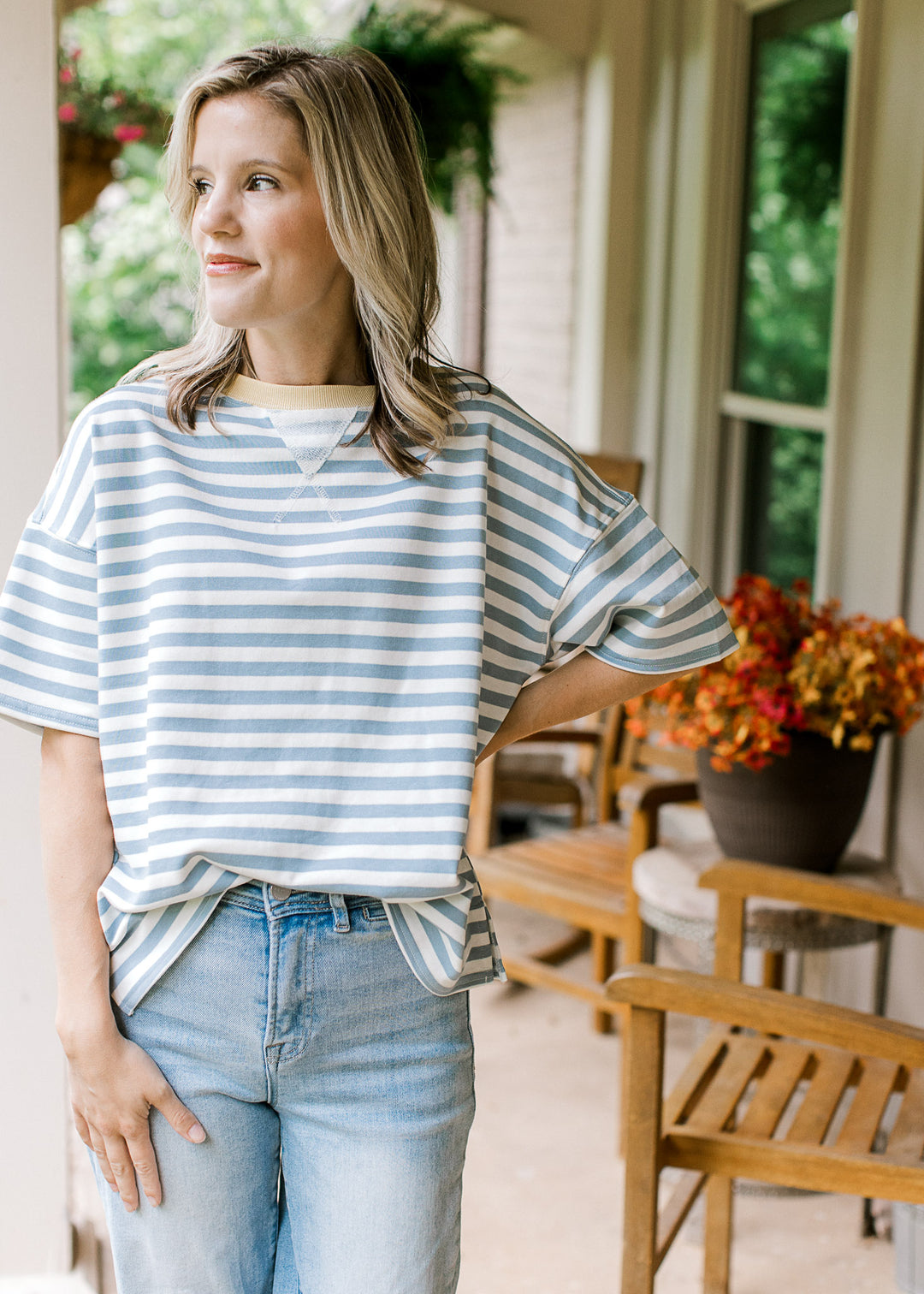 Model wearing a lightweight, short sleeve dusty blue and white striped top with pale yellow neck.