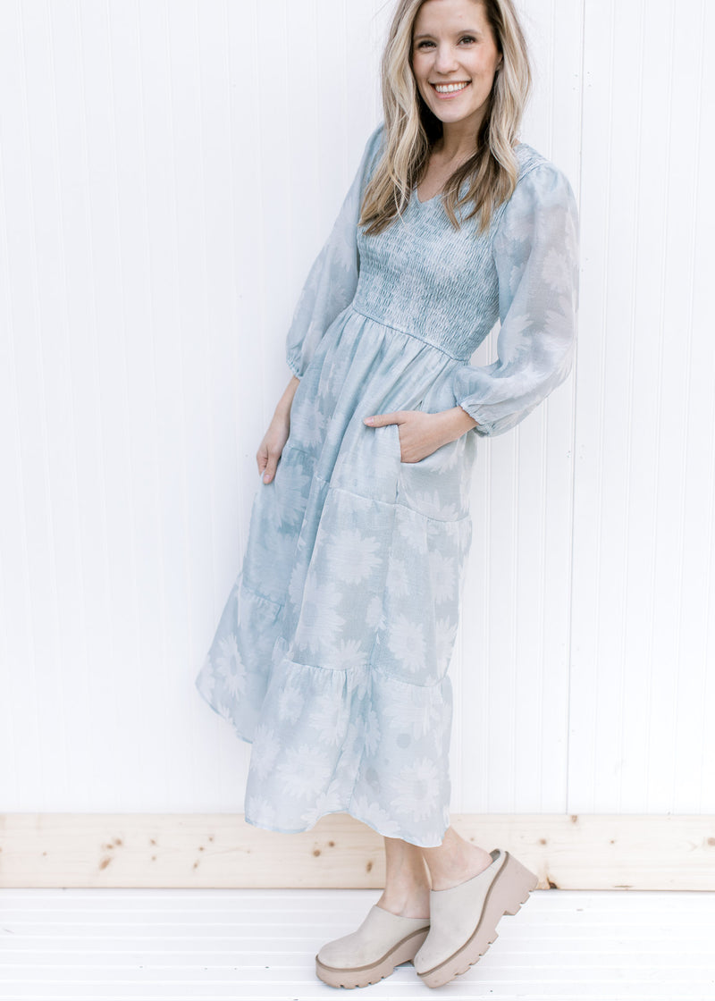 Model wearing mules with a sage dress with a smocked bodice, 3/4 sleeves and a faint daisy print.