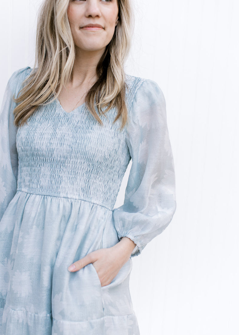 Close up of smocked bodice and sheer sleeves on a sage dress with a faint daisy print.
