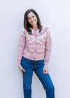 Model wearing jeans with a dusty pink button up sweater with fair isle pattern and long sleeves.