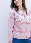 Close up of fair isle pattern at yolk of a dusty pink button up sweater with long sleeves.