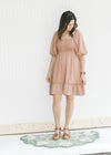 Model wearing an above the knee mauve dress with a smocked bodice and bubble short sleeves.