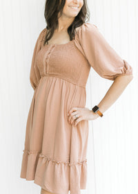 Close up of smocked bodice and bubble short sleeves on an above the knee mauve dress.