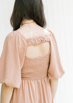 Back view of ruched strap, smocked back and bubble short sleeves on a dusty mauve dress. 