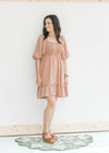 Model wearing sandals with a mauve dress with a smocked bodice and bubble short sleeves.