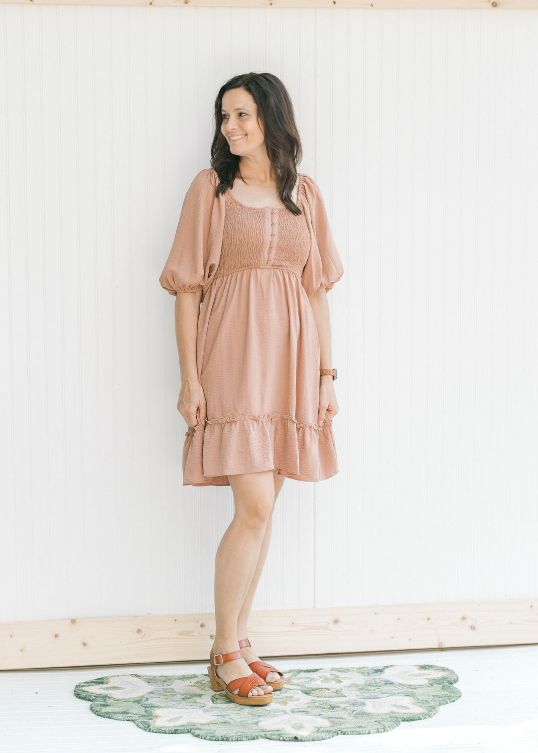 Model wearing sandals with a mauve dress with a smocked bodice and bubble short sleeves.