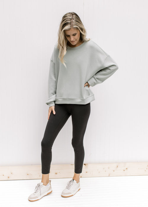 Model wearing a soft sage lightweight sweatshirt with long sleeves and a round neck. 