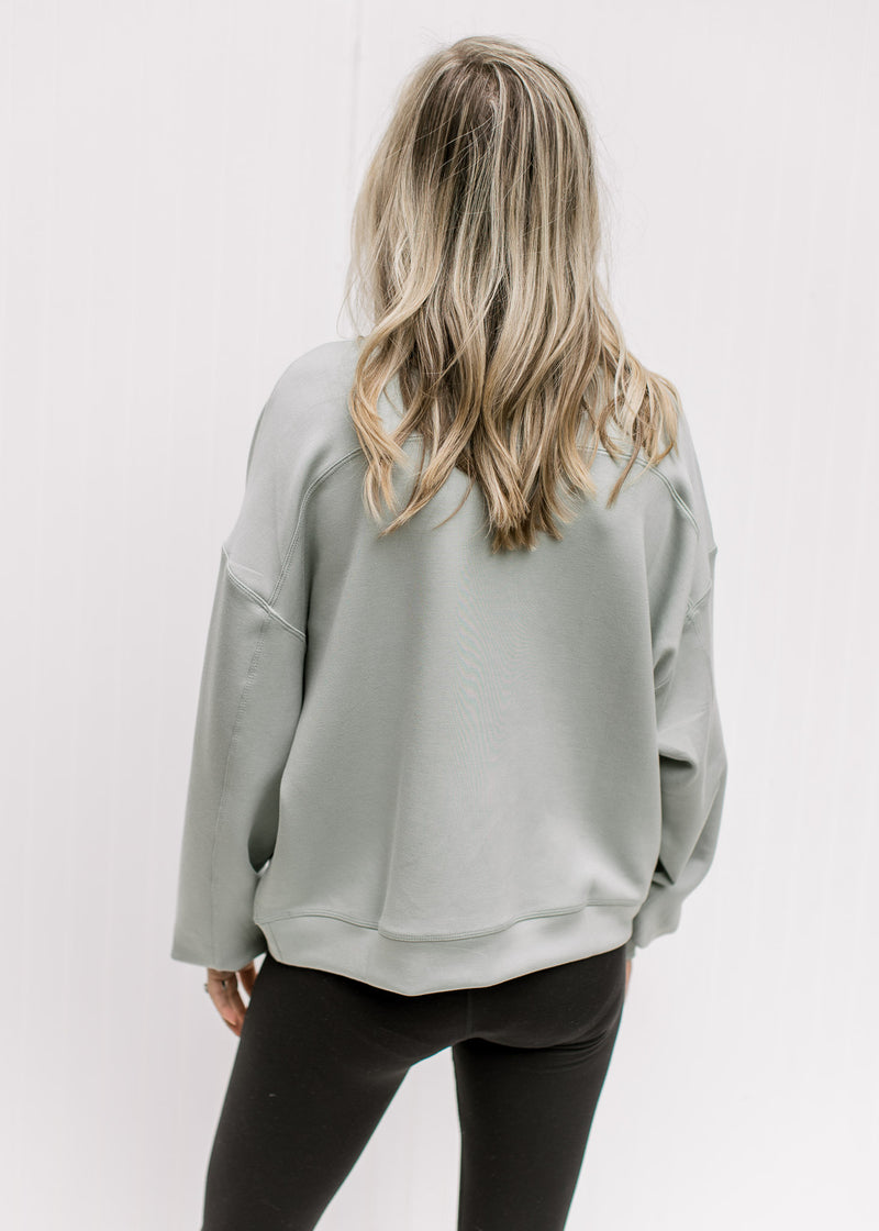 Back view of Model wearing a sage lightweight sweatshirt with long sleeves and a round neck. 