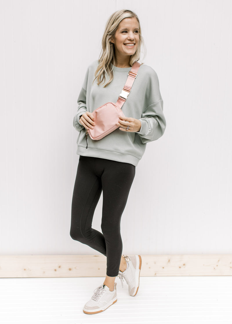 Model wearing leggings and a soft sage sweatshirt with long sleeves and a round neck. 