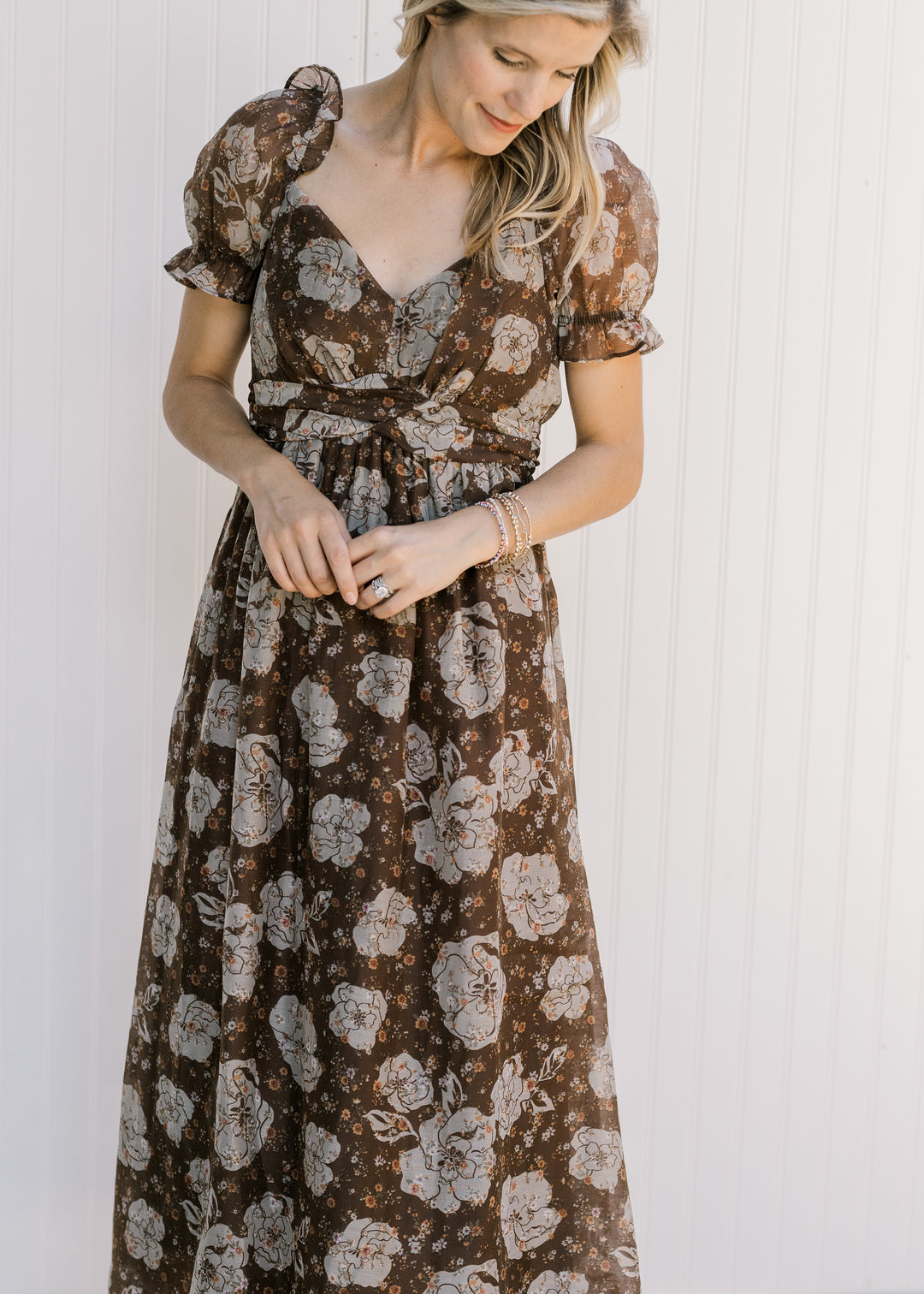 Model wearing a brown midi with cream floral, v-neck, sheer puff short sleeves and a smocked back.