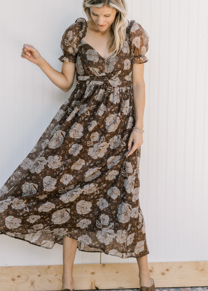 Model wearing a brown midi with cream floral, v-neck, sheer puff short sleeves and a flowy skirt.