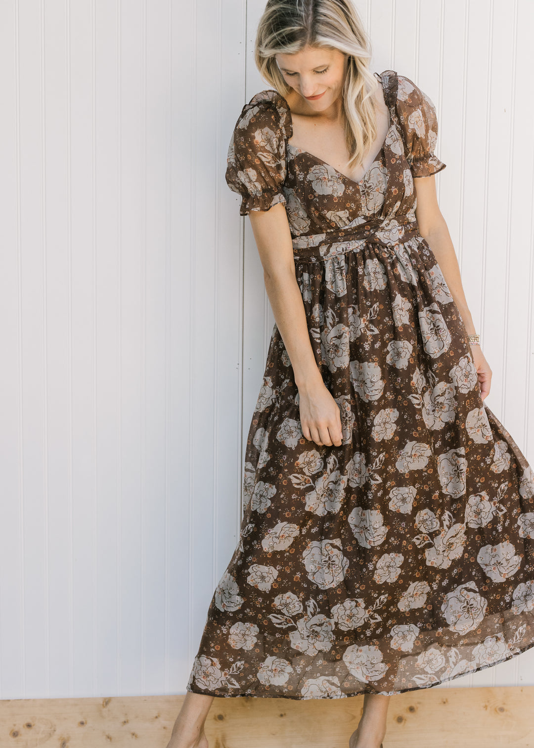Model wearing a brown flowy midi with cream floral, v-neck and sheer puff short sleeves. 