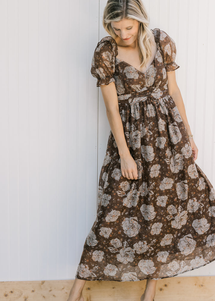 Model wearing a brown flowy midi with cream floral, v-neck and sheer puff short sleeves. 