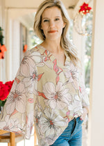 Model wearing a pale lime colored top with cream and coral flowers and sheer 3/4 bell sleeves. 