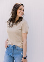 Close up of Model wearing a ecru and camel crew neck tee with stripes and short sleeves. 