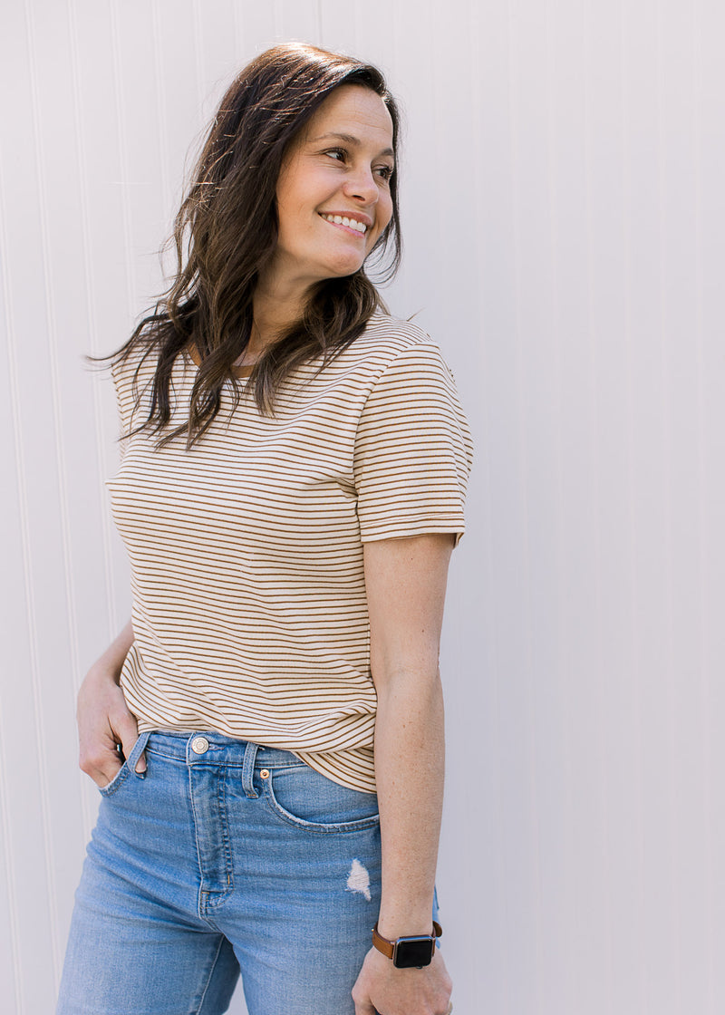 Close up of Model wearing a ecru and camel crew neck tee with stripes and short sleeves. 