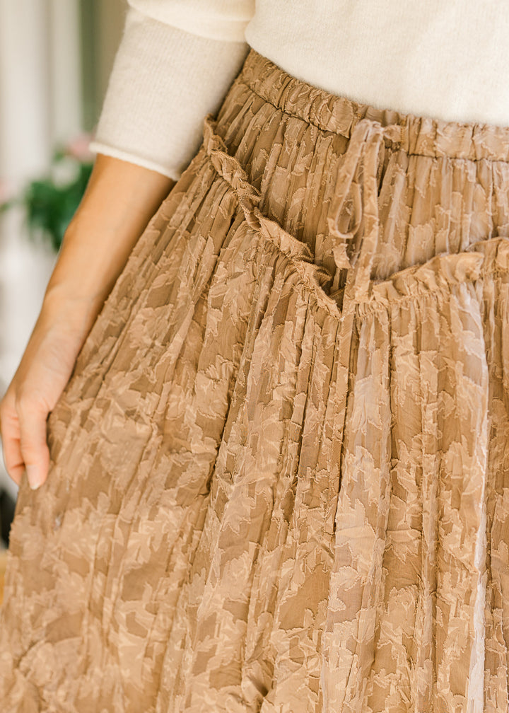 Close up of tie elastic waist and v-shaped ruffle at the waist of a toffee midi with subtle lace. 
