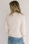 Back view of Model wearing a lightweight cream sweater with long sleeves and a mock neckline.