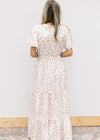 Back view of Model wearing a white v-neck maxi with pale pink embroidered floral and elastic waist.