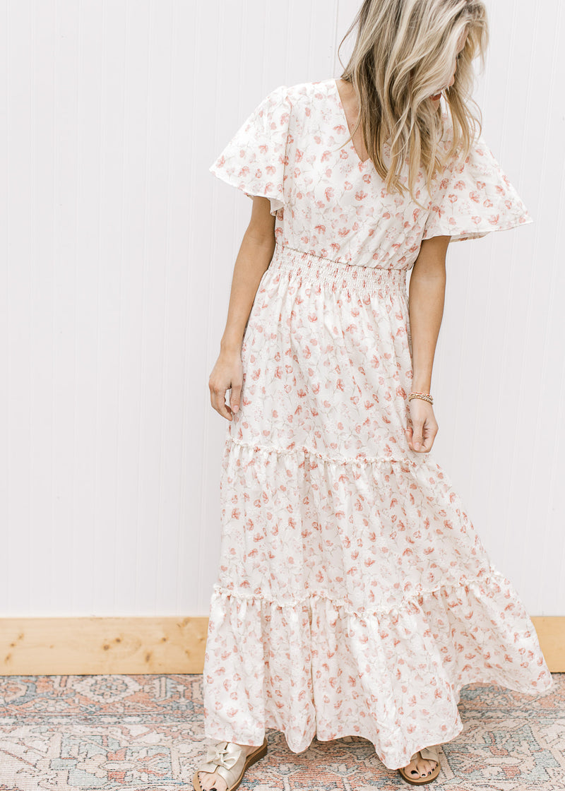 Model wearing a white v-neck maxi with pale pink embroidery, short sleeves and elastic waist.