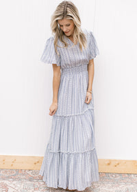 Model wearing a V-neck white maxi with a pale blue print, short sleeves and a wide elastic waist. 