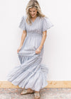Model wearing a flowy white maxi with a pale blue print, short sleeves and a wide elastic waist. 