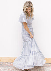 Model wearing a white maxi with a pale blue print, short sleeves and a wide elastic waist. 