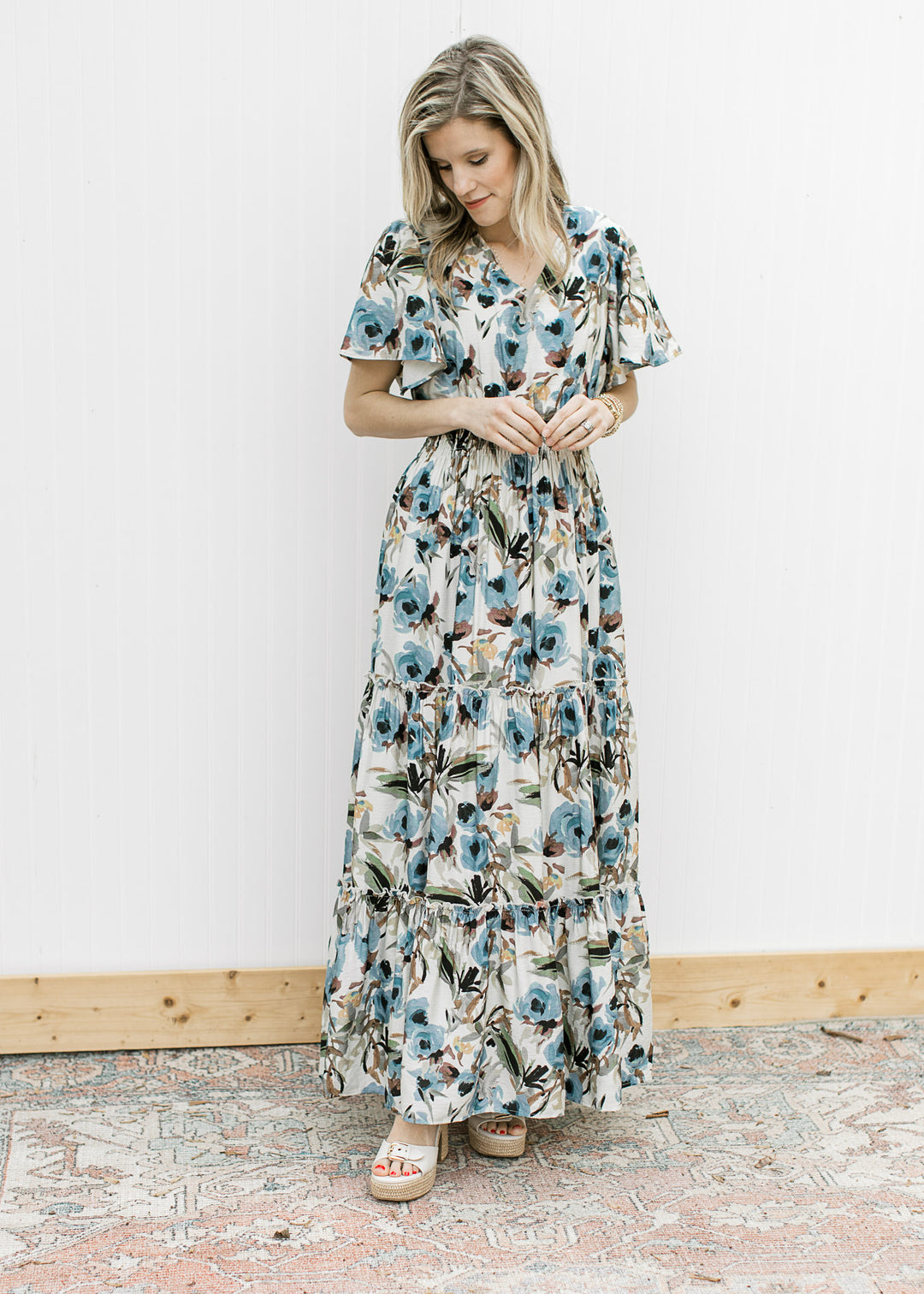 Model wearing a cream v-neck maxi with watercolor floral, flutter short sleeves and elastic waist. 