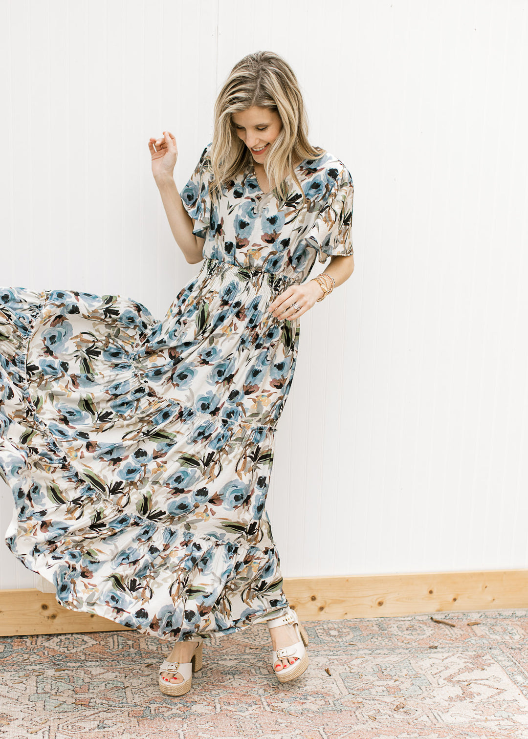 Model wearing sandals and a cream v-neck maxi with watercolor floral and flutter short sleeves. 