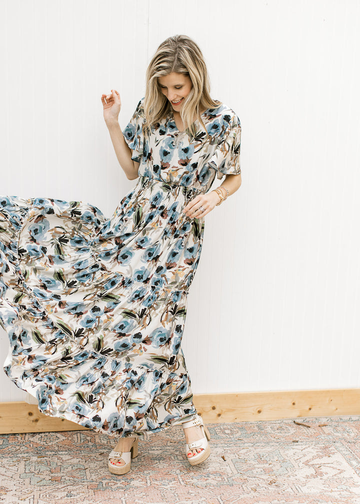 Model wearing sandals and a cream v-neck maxi with watercolor floral and flutter short sleeves. 