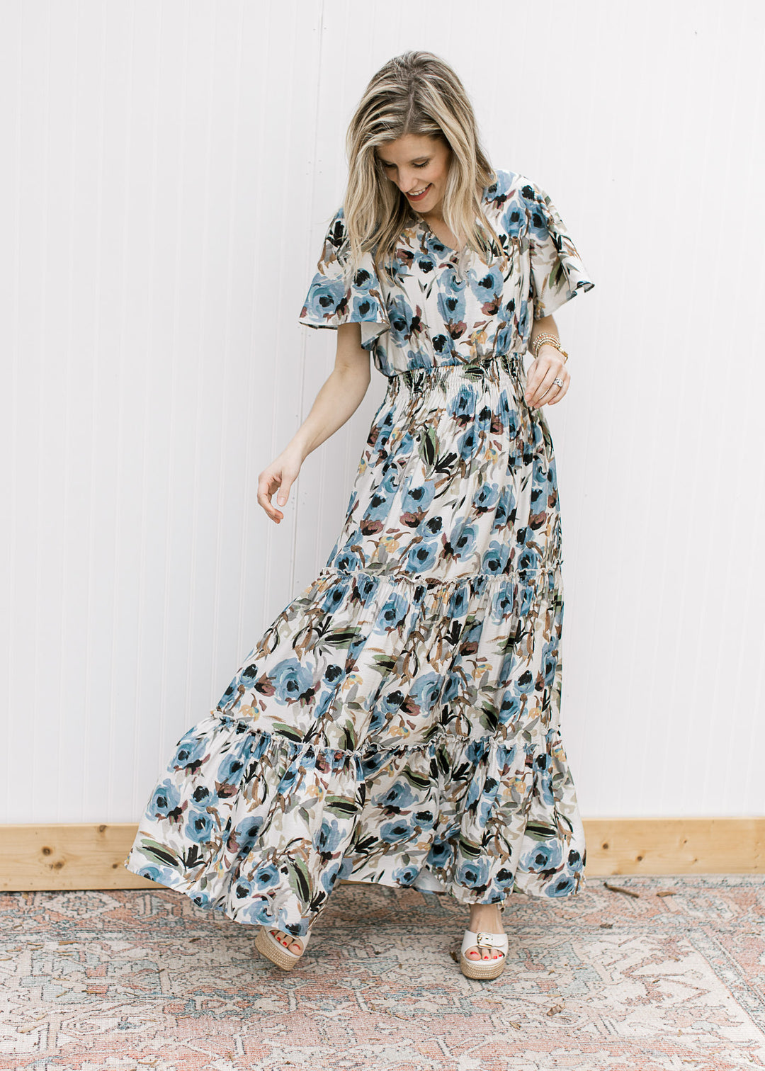 Model wearing a cream v-neck maxi with watercolor floral, tiered skirt and elastic waistband. 