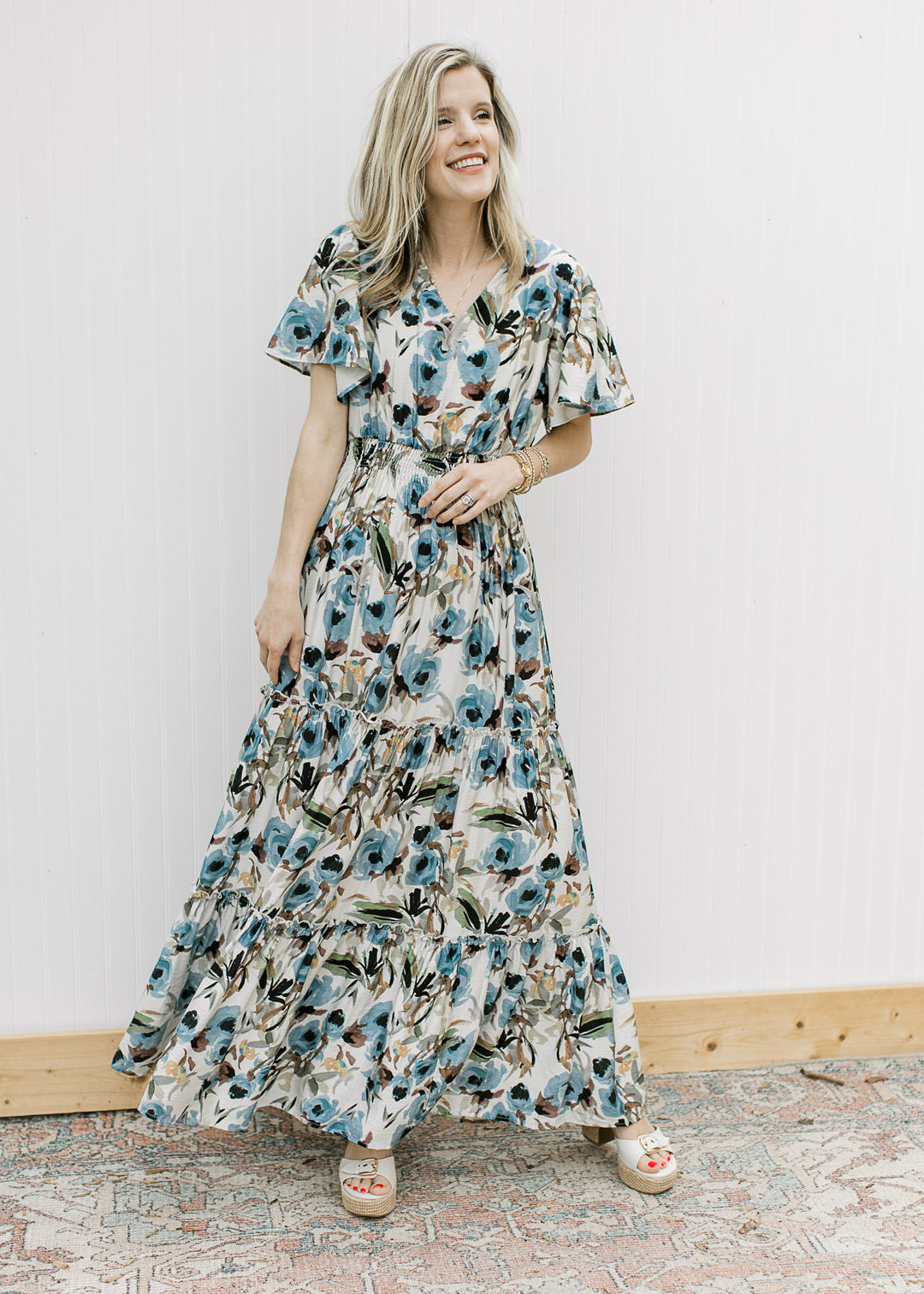 Model wearing a lined, cream v-neck maxi with watercolor floral, short sleeves and elastic waist. 