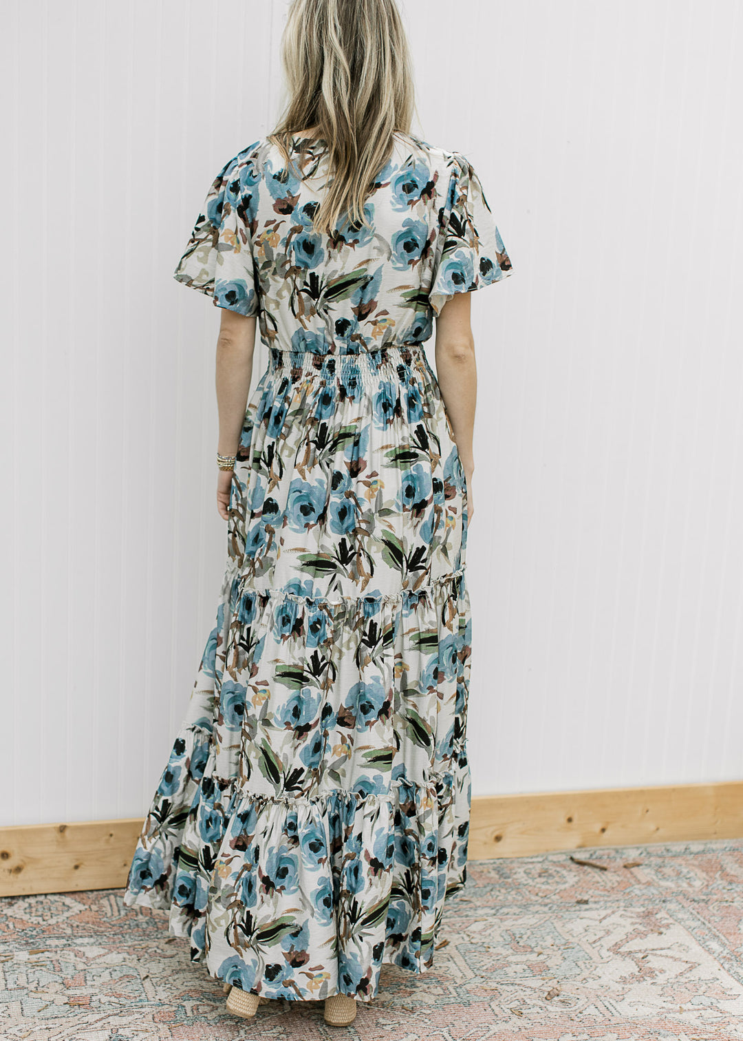 Back view of Model wearing a cream maxi with watercolor floral, flutter short and elastic waistband.