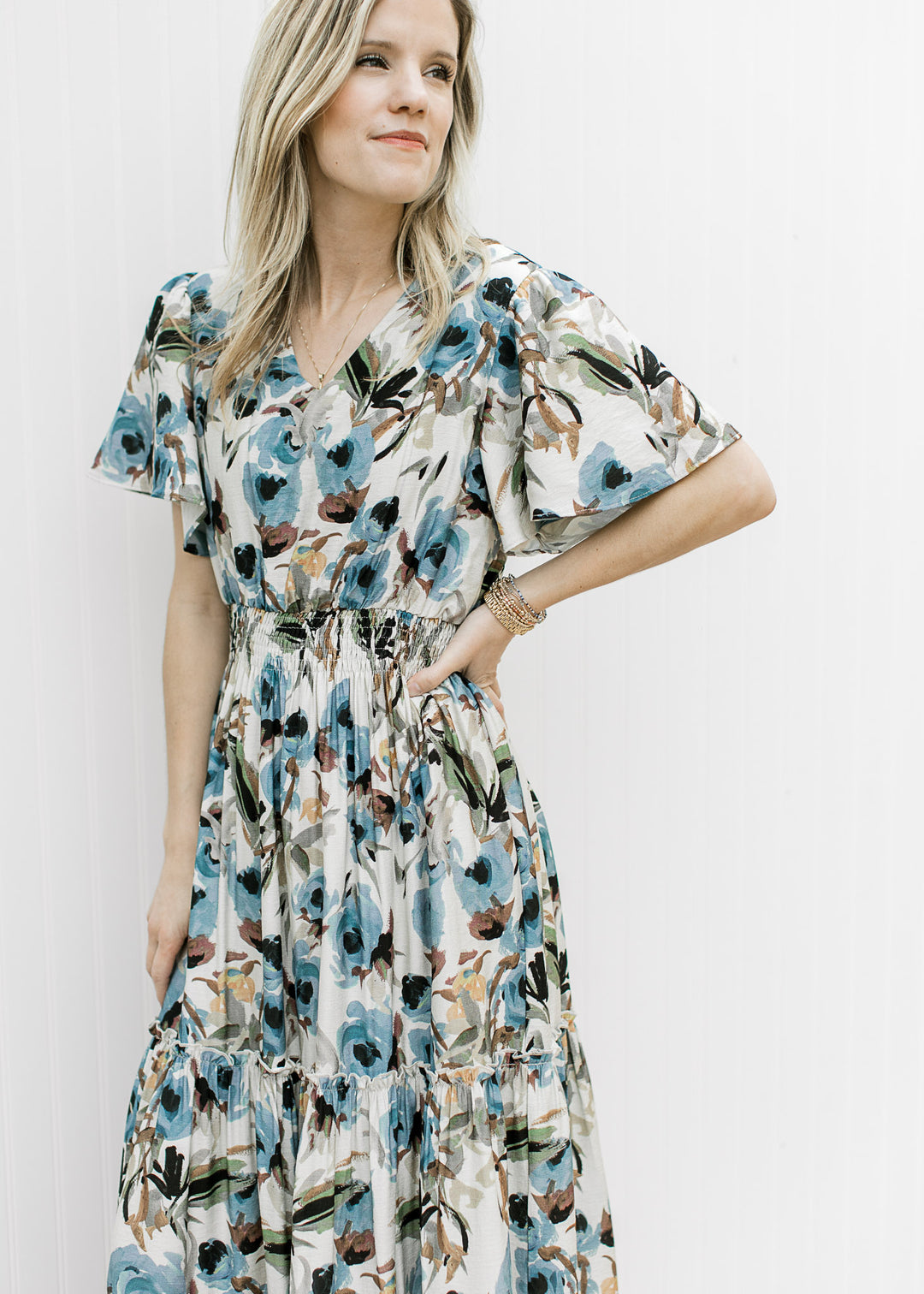Model wearing a tiered cream v-neck maxi with watercolor floral, flutter short and elastic waist.